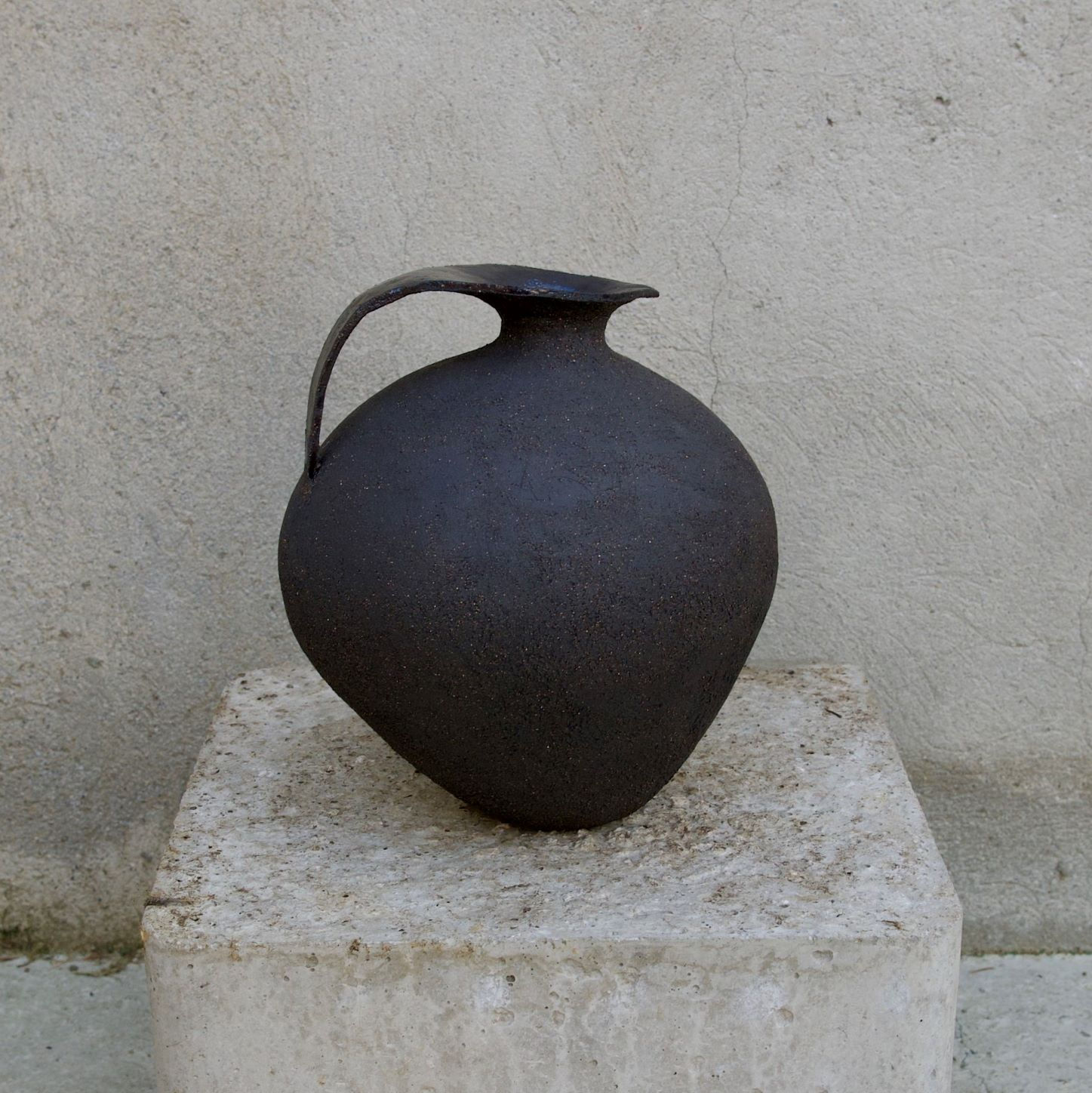 Pichet sculptural artisanal en grès noir sur stèle grise