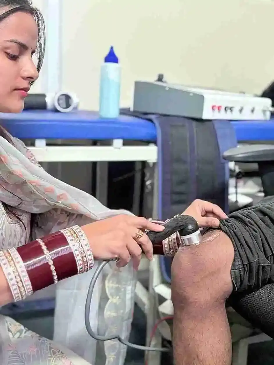 Close-up of a therapist applying ultrasound therapy to a patient's knee.