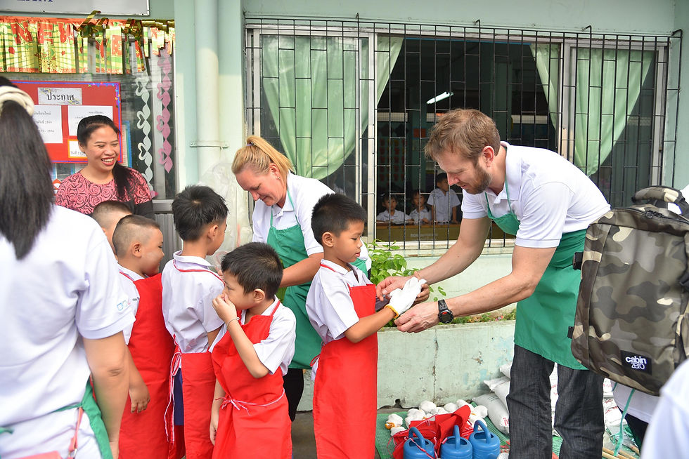 Thumbnail: Volunteers assisting young schoolchildren in red aprons during a hands-on CSR event at a Phuket school.