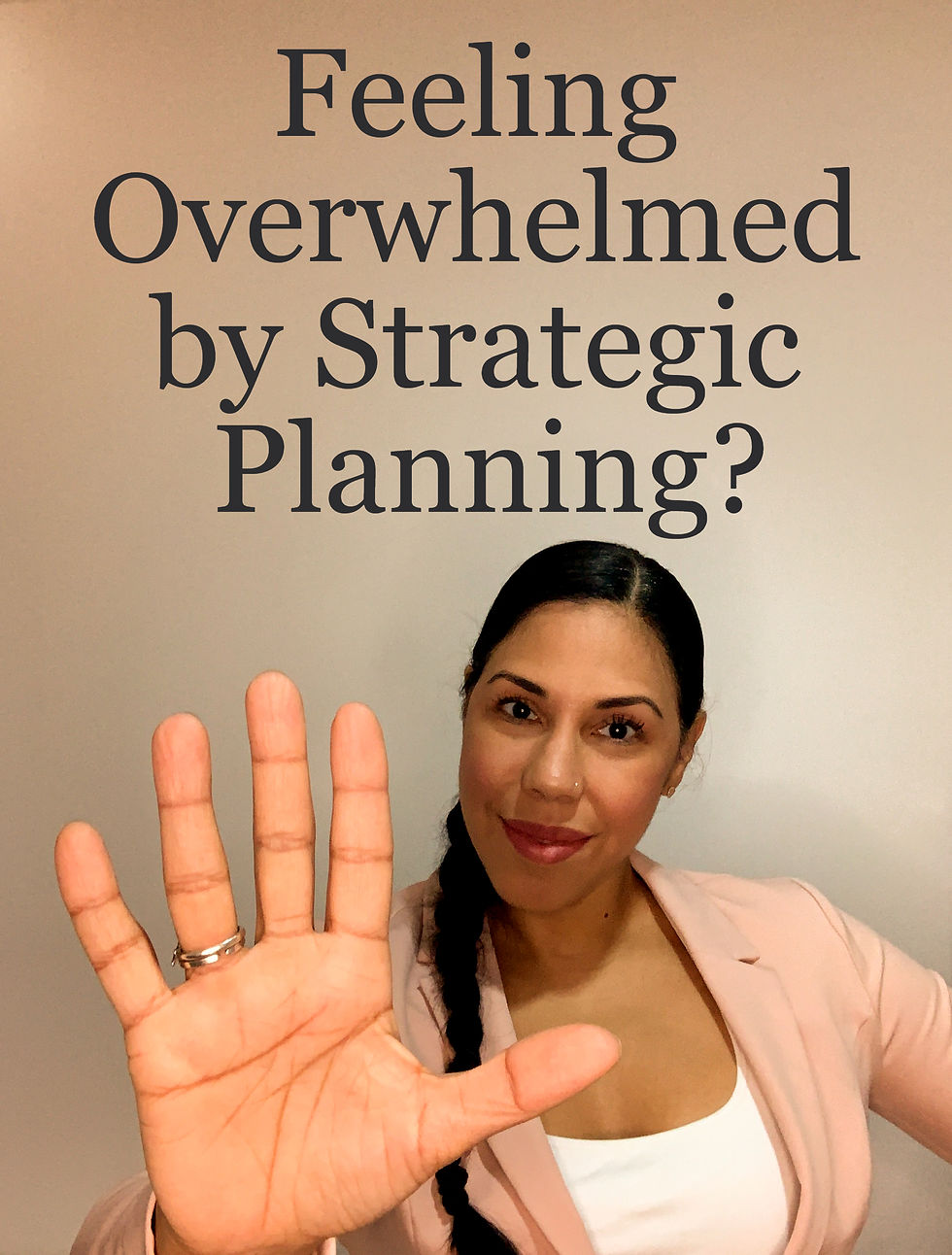 Woman in pink blazer holds up a hand, smiling. Text above reads "Feeling Overwhelmed by Strategic Planning?" Neutral background.
