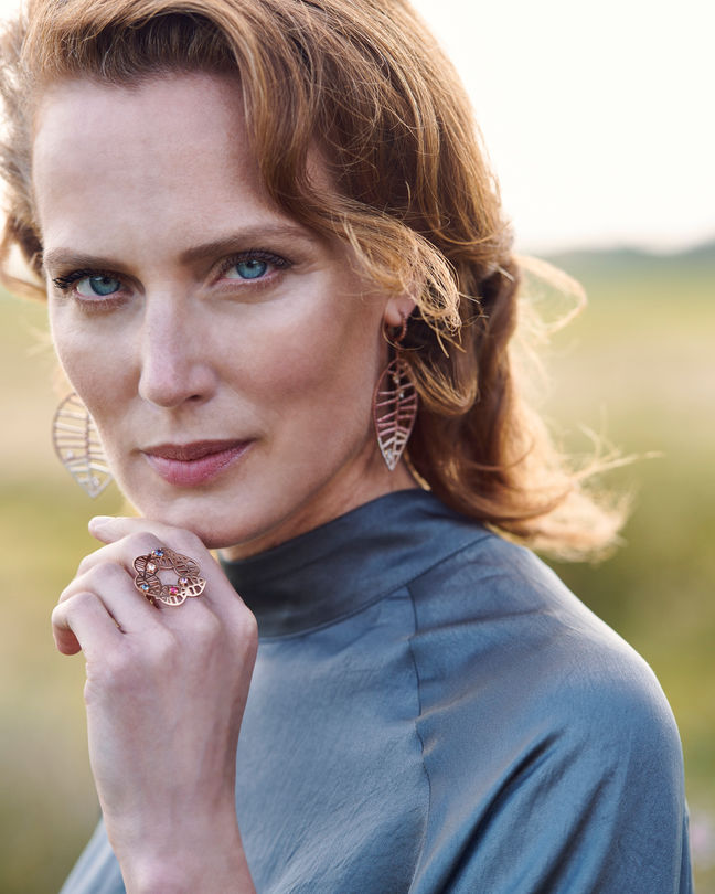 Woman resting her hand below her chin, wearing the Beech Nuance Ring in rose gold, set with corundum and spinel