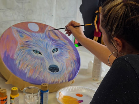 Art Student painting with acrylics a wolf on a drum