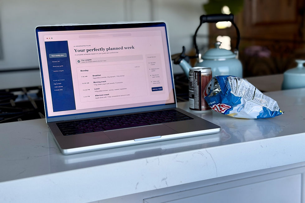 A laptop on a kitchen counter showing a perfectly planned week of meals, next to a can of soda and an open bag of chips.