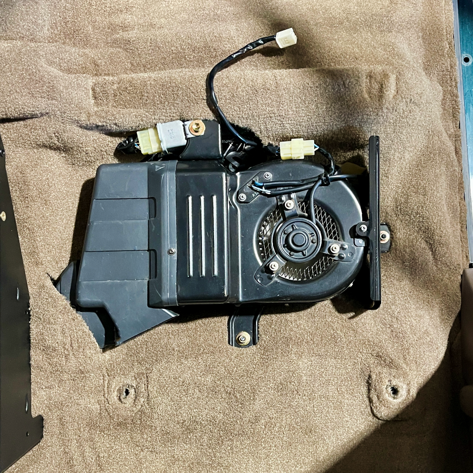 The 80 Series blower motor and heater core located under the passenger seat in US trucks.