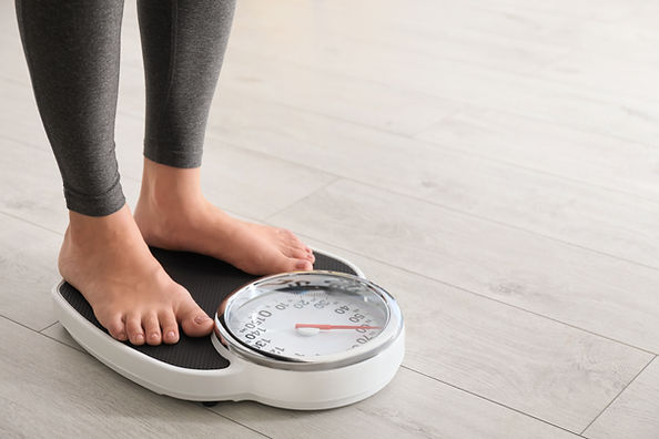 Woman standing on scales indoors, space 