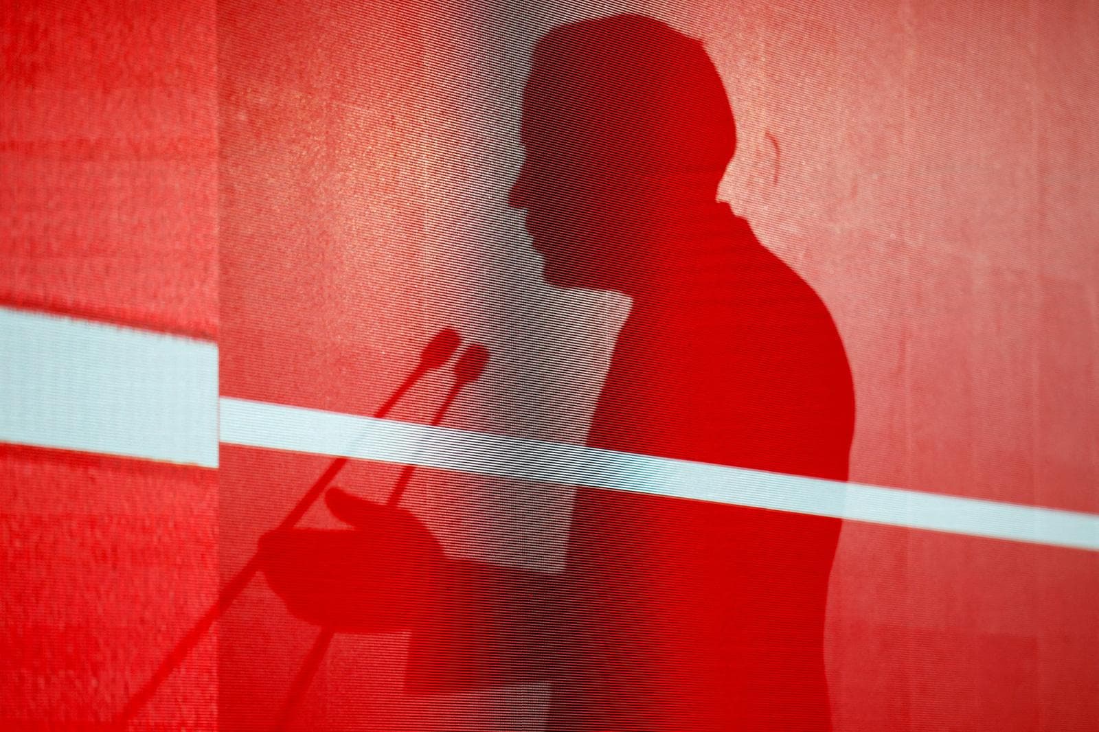 The shadow of Mark Carney against a red backdrop during a visit to Beijing