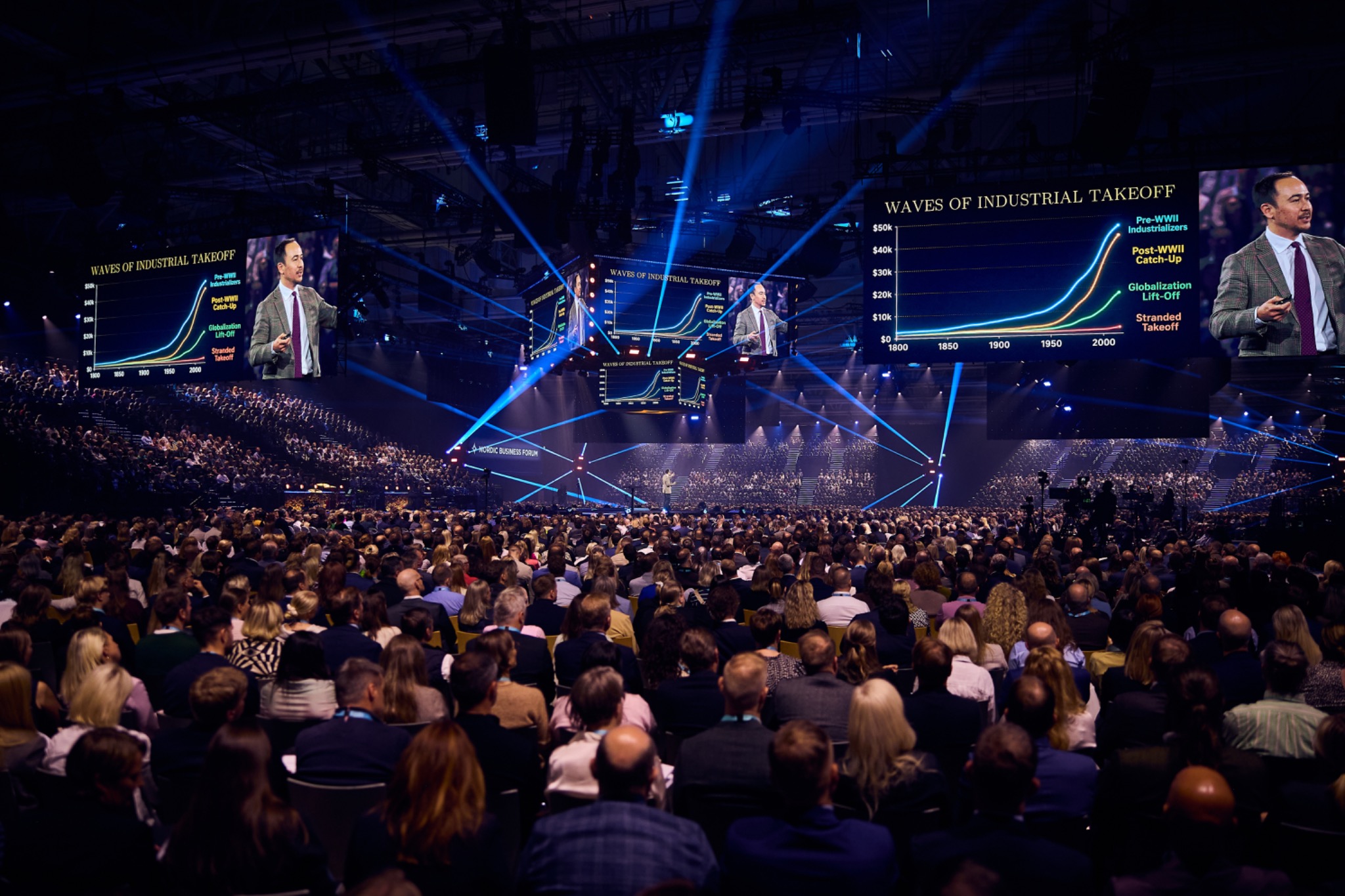 Michael Beckley on stage at Nordic Business Forum in Helsinki, with his presentation on large screens above the audience