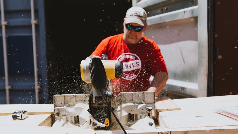 Volunteer cutting lumber on a rebuild project