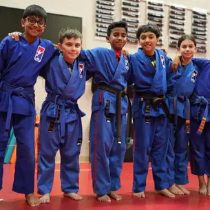 a group of school-age kids in a karate class with their arms around each other