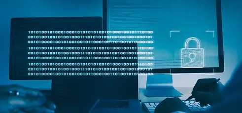 Two individuals are focused on computer screens that display rows of binary code and a prominent digital padlock symbol, suggesting a secure coding environment live demo session in a dimly lit blue office.