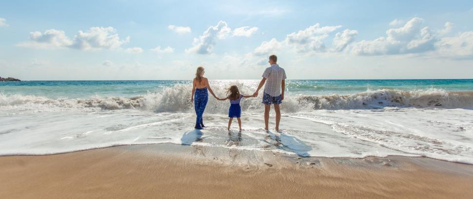family-holding-hands-facing-the-waves-on-a-sunny-beach-day..jpg