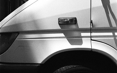 A white van is parked in front of a buil