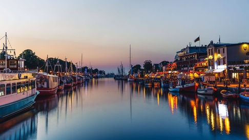 Abendliche Hafenansicht vom Alten Strom mit Booten und Restaurants am Wasser
