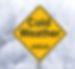 A yellow diamond-shaped road caution sign that reads: “Cold Weather AHEAD” with a snowy scene in the background.
