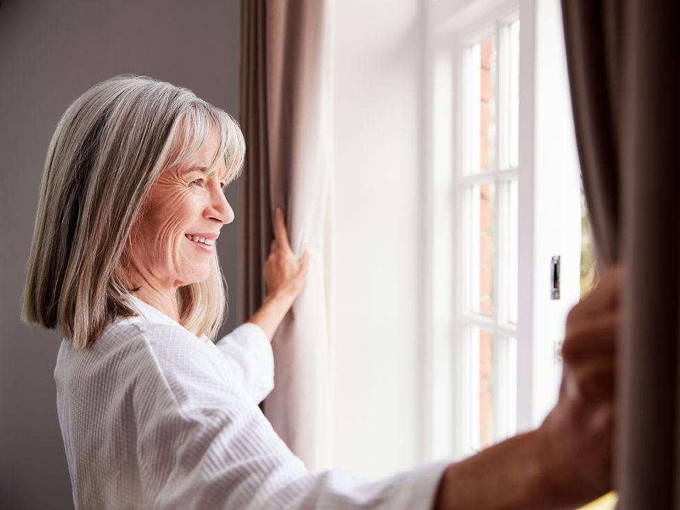 Photo of a smiling woman opening window curtains.
