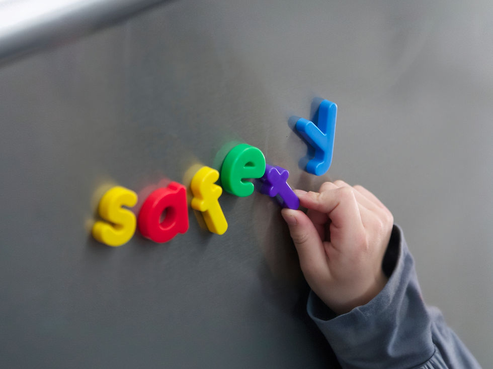 Close-up photo of a child's hand spelling the word safety with refrigerator magnets.