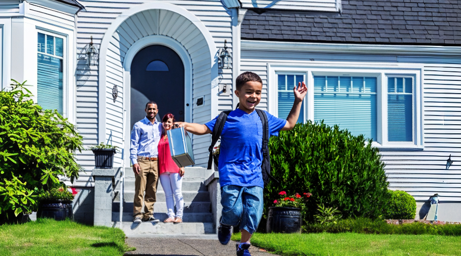 A man and woman watch is their child skips down their font walk. The child is wearing a backpack.