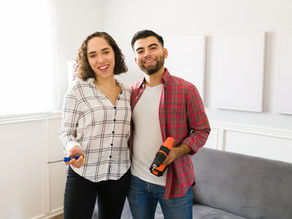 Photo of a young man and woman holding home improvement tools.