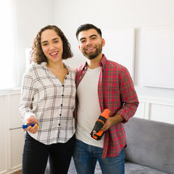 Photo of a young man and woman holding home improvement tools.
