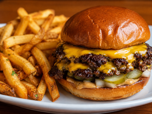 Double smash cheeseburger with melted cheese on a toasted brioche bun served with crispy seasoned French fries