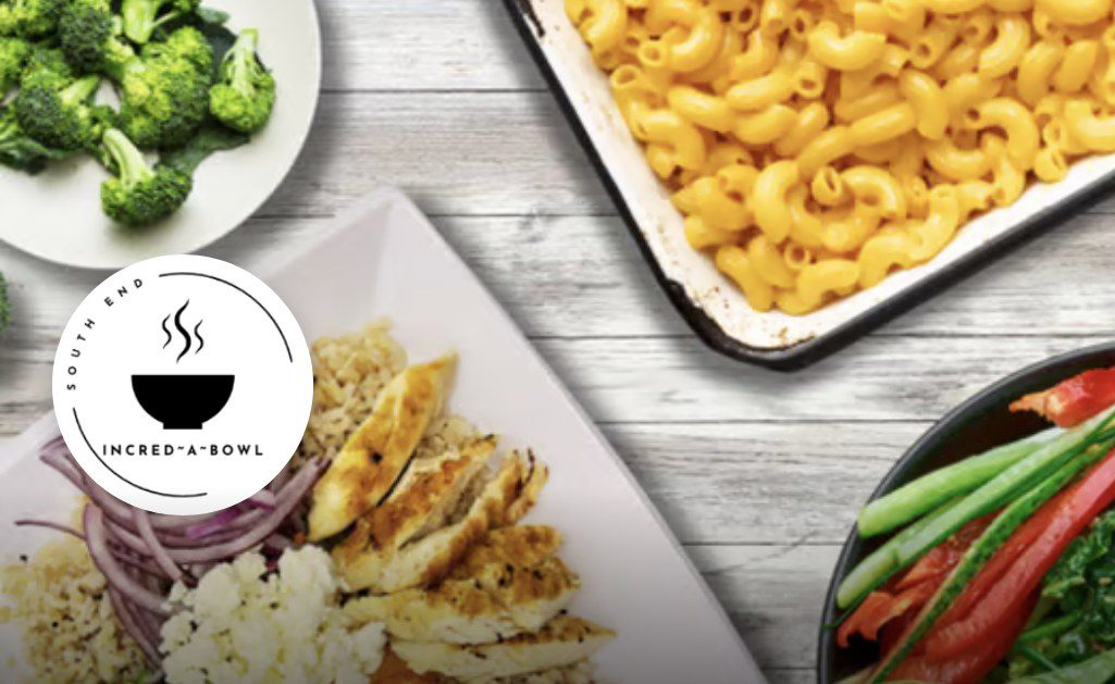 Incred-A-Bowl bowls on a wooden table: chicken rice bowl, mac and cheese, broccoli and fresh veggies