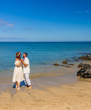 Couple dances on the shoreline during their wedding photos at Waikoloa beach in Hawaii.