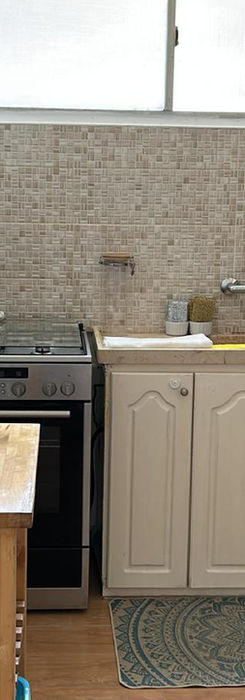 Кухня со светлыми шкафами, плитой и раковиной