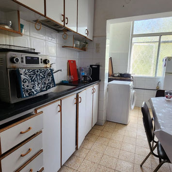 Кухня с белыми шкафами, техникой и обеденной зоной