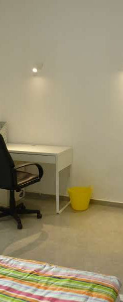 Светлая комната с письменным столом, стулом и кроватью.