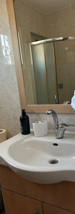 Ванная комната с раковиной, зеркалом и полотенцами.