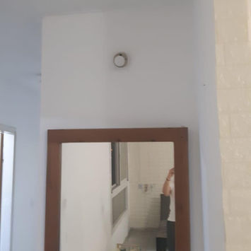 Квадратное зеркало в деревянной раме на белой стене