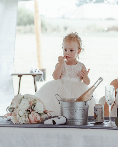 A flower girl sitting on top of a table in a white dress