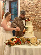 Bride in white and groom in camouflage cutting the wedding cake.