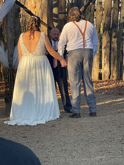 A bride and groom holding hands in front of a wedding officiant