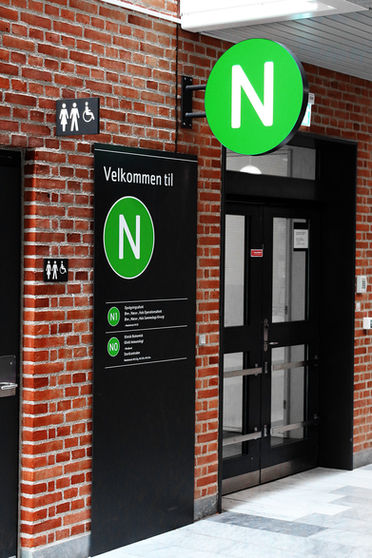 Rundt vingeskilt med grøn baggrund og bogstavet N samt sort pylon med informationer i grøn