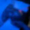 close up of a woman in a black light aura receiving skincare treatment