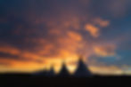 Tipis in against a sunset
