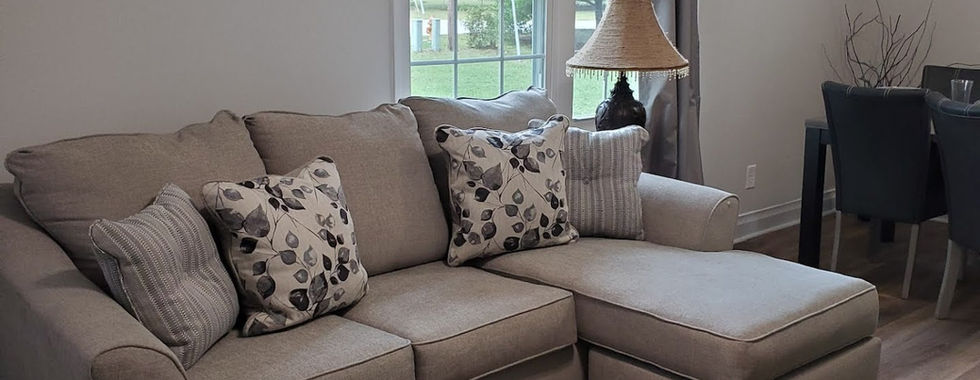A living room with a rug, window and sectional.