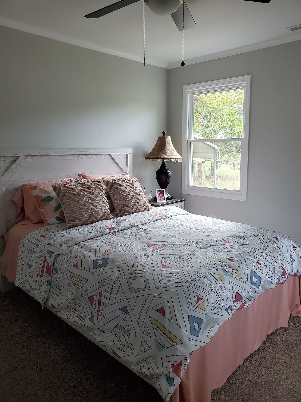A bedroom includes a window and ceiling fan.