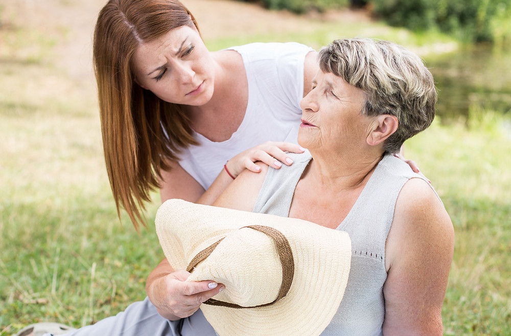 A senior women is experiencing heat-related illness symptoms and is resting while help is on the way.