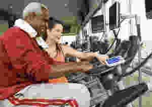 A senior citizen is working with a personal trainer for aerobic exercise.