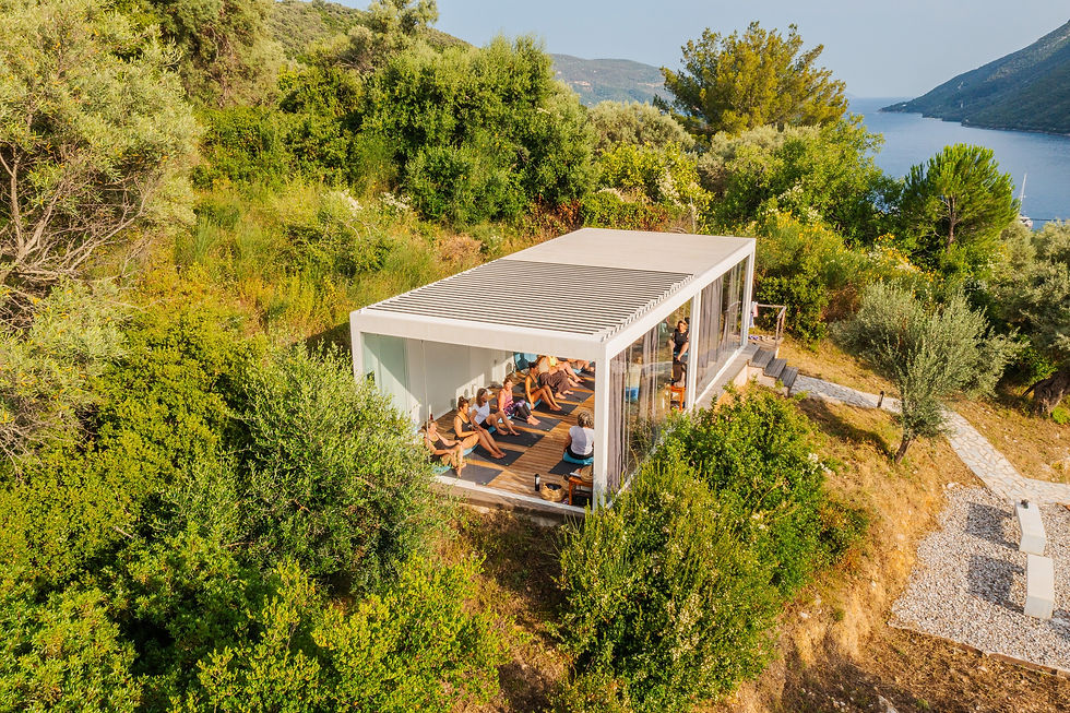 An open building sits on a hillside, and people inside are doing a yoga class.