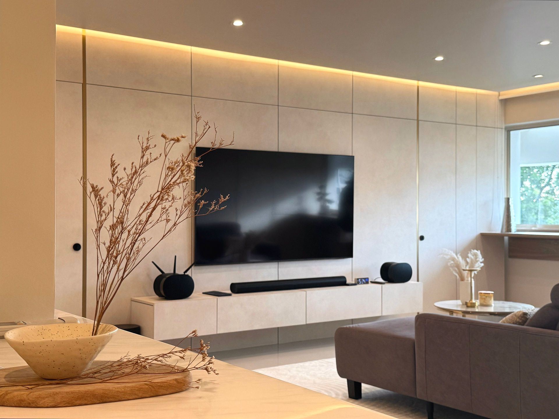 Modern luxury Yishun HDB living room featuring a full-height TV feature wall, warm lighting and refined neutral finishes