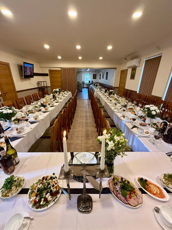 Long tables set with food for a banquet; two candles in the middle.