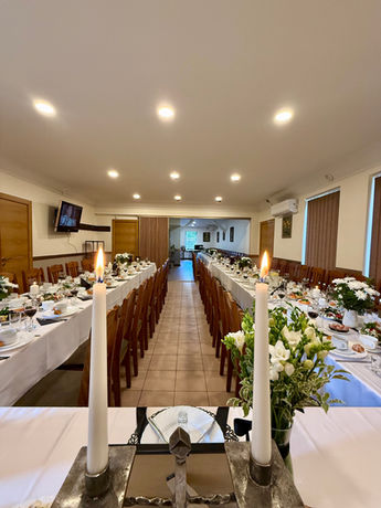 Long tables set for a celebration with burning candles and floral arrangements