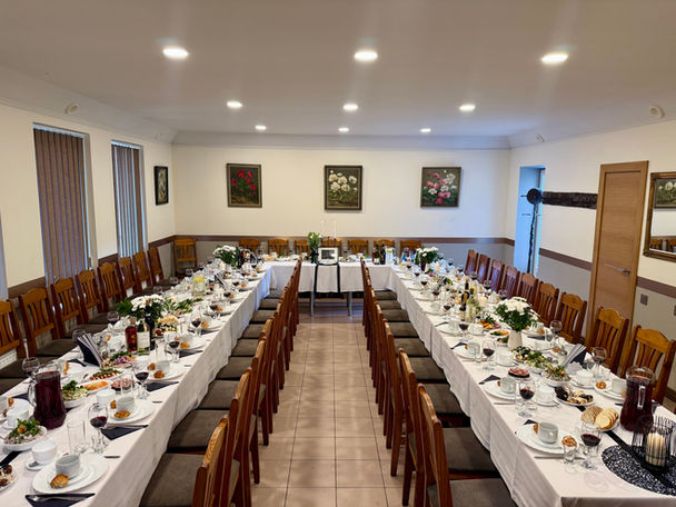 Long dining tables set for a banquet; white tablecloths, flowers, decor.