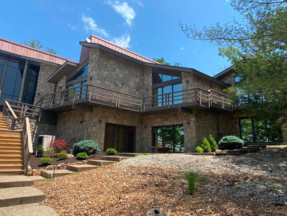 Contemporary stone home with rock and mulch landscaping and custom plants.