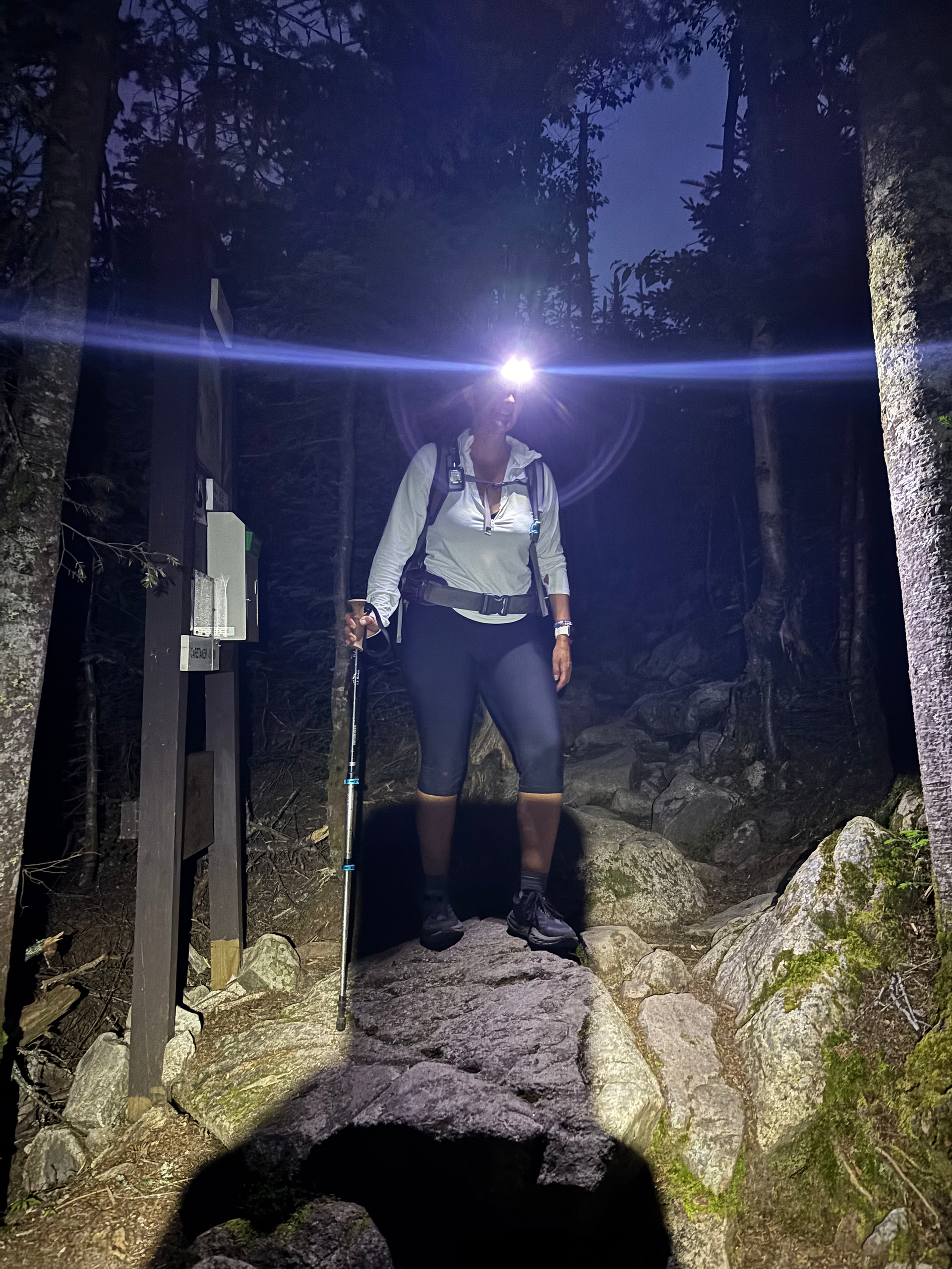 Hiker with headlamp walking down to Guyot Campground near the Bonds in New Hampshire. 