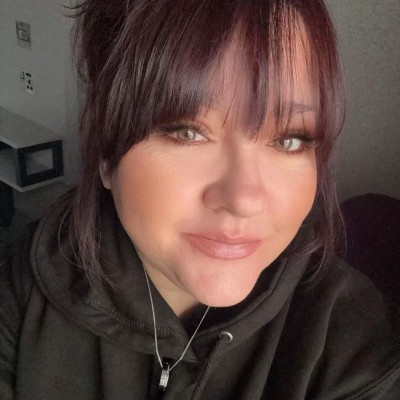 photo of Lisa B. Close up selfie, smiling with dark hair and fringe.
