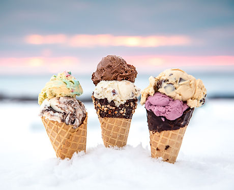 Three ice cream cones with a variety of hand dipped ice cream flavors, stacked in waffle cones.